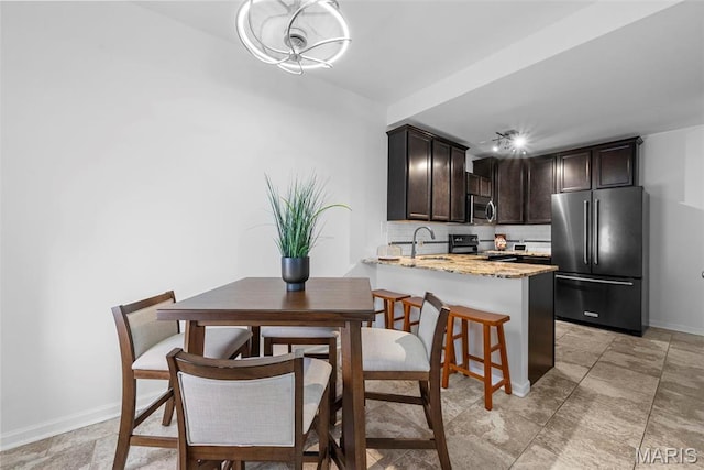 4366 W Pine Blvd Unit Cw, Saint Louis, MO 63108 - kitchen with stainless steel appliances, dark brown cabinetry, tasteful backsplash, light stone countertops, and a peninsula