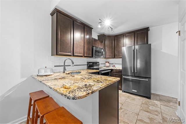 4366 W Pine Blvd Unit Cw, Saint Louis, MO 63108 - kitchen with stainless steel appliances, a sink, tasteful backsplash, dark brown cabinetry, and light stone counters