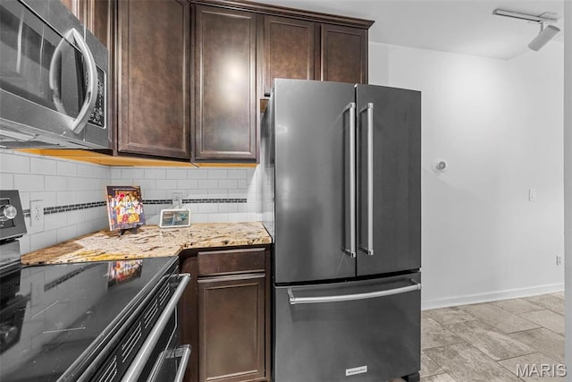 4366 W Pine Blvd Unit Cw, Saint Louis, MO 63108 - kitchen featuring appliances with stainless steel finishes, light stone counters, decorative backsplash, dark brown cabinetry, and baseboards
