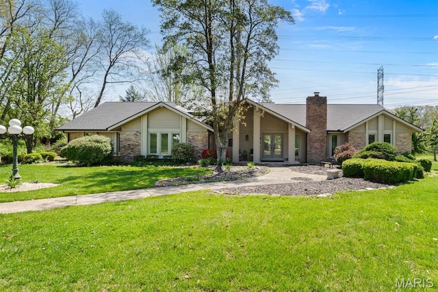 view of front of home with french doors, a chimney, a front lawn, and brick siding