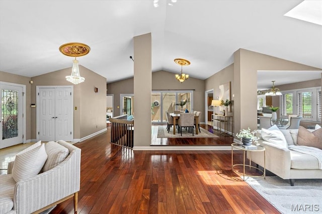 living area featuring a chandelier, lofted ceiling, hardwood / wood-style flooring, and baseboards