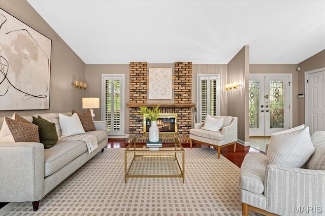 living area with wood finished floors, a brick fireplace, and french doors