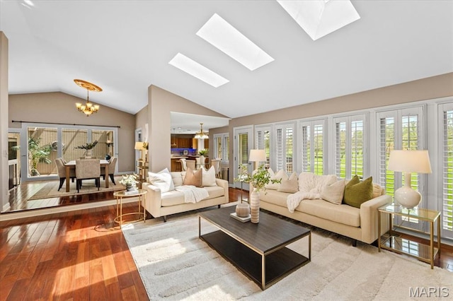living room featuring a chandelier, lofted ceiling, wood-type flooring, a skylight, and healthy amount of natural light