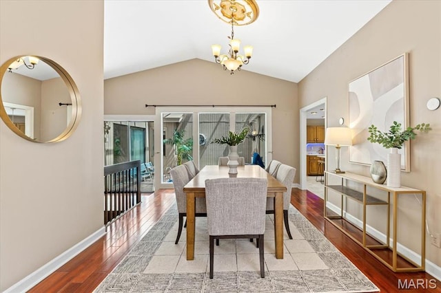 dining room with a chandelier, wood finished floors, vaulted ceiling, and baseboards