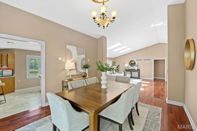 dining area featuring hardwood / wood-style floors, a chandelier, baseboards, and vaulted ceiling