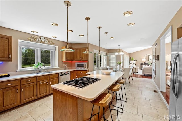 kitchen featuring a sink, appliances with stainless steel finishes, brown cabinetry, light countertops, and vaulted ceiling