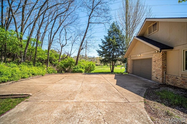 view of home's exterior featuring asphalt driveway, brick siding, and an attached garage