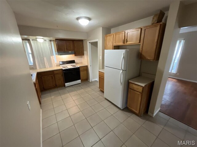 10115 Saffron Dr, Saint Louis, MO 63136 - kitchen featuring white appliances, under cabinet range hood, light countertops, and decorative backsplash