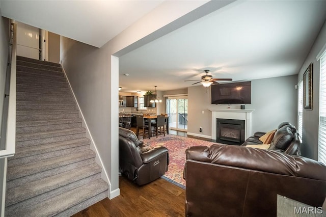 1338 Orchard Lakes Cir, Belleville, IL 62220 - living area with stairway, baseboards, dark wood-style floors, a ceiling fan, and a glass covered fireplace