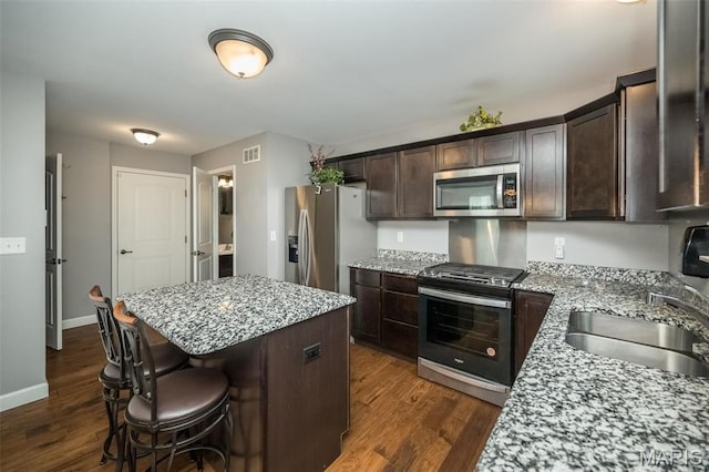 1338 Orchard Lakes Cir, Belleville, IL 62220 - kitchen with stainless steel appliances, a kitchen island, dark brown cabinets, a kitchen breakfast bar, and dark wood-style floors