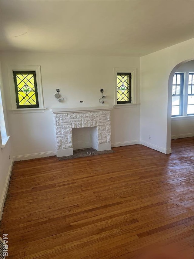 3460 Oakdale Ave, Saint Louis, MO 63121 - unfurnished living room featuring arched walkways, baseboards, and wood finished floors