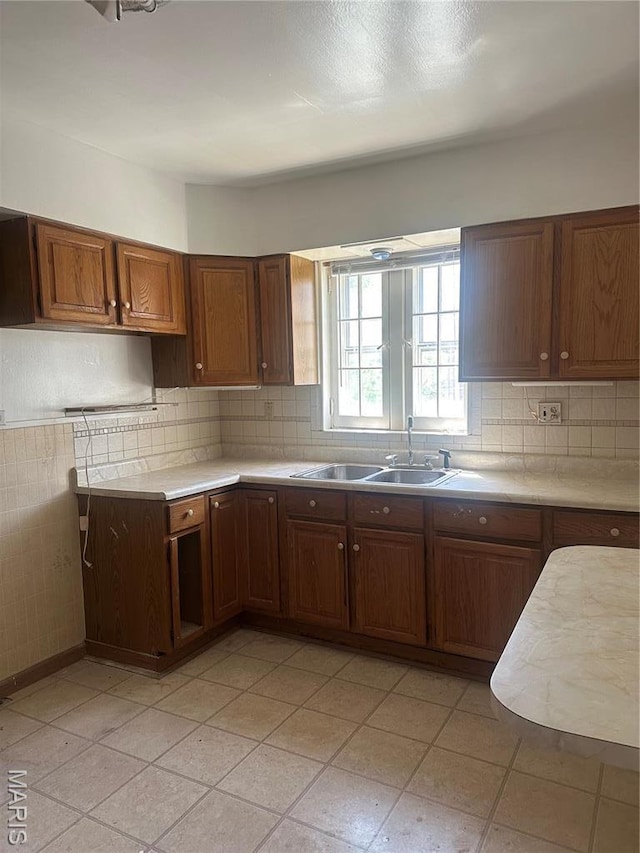 3460 Oakdale Ave, Saint Louis, MO 63121 - kitchen featuring light countertops, a sink, backsplash, and brown cabinetry
