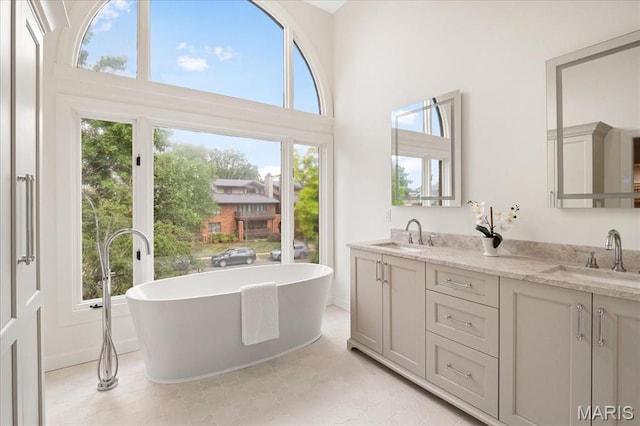 139 N Central Ave Unit P, Saint Louis, MO 63105 - bathroom with double vanity, a freestanding tub, a high ceiling, and tile patterned flooring