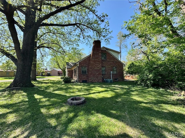 view of property exterior featuring a yard, a chimney, an outdoor fire pit, and brick siding