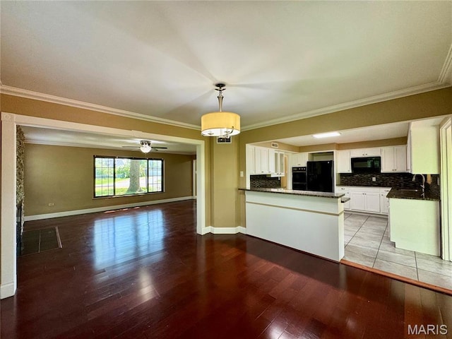 kitchen with black appliances, open floor plan, ornamental molding, a peninsula, and a sink