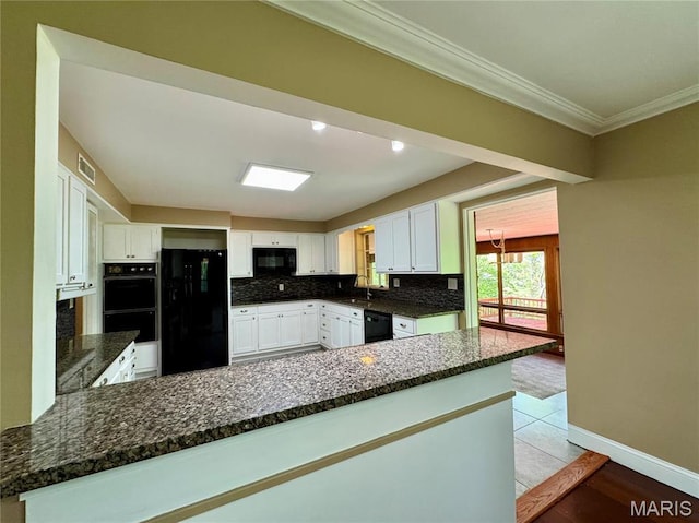 kitchen featuring black appliances, crown molding, dark stone countertops, white cabinets, and backsplash