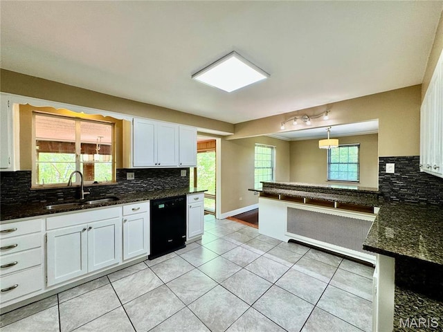 kitchen with black dishwasher, a sink, backsplash, and white cabinetry