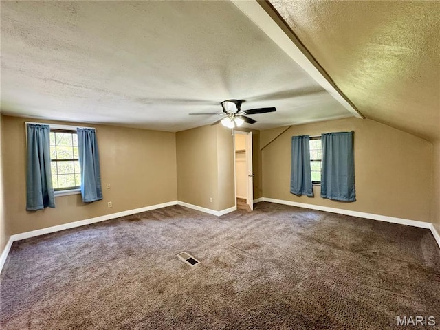 carpeted spare room with a textured ceiling, ceiling fan, baseboards, and vaulted ceiling