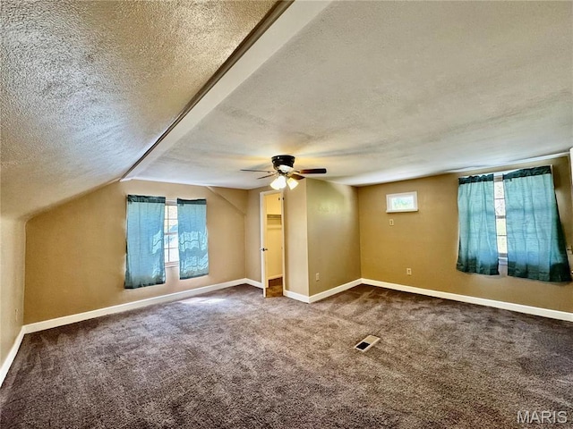 additional living space with a textured ceiling, a ceiling fan, healthy amount of natural light, carpet flooring, and baseboards