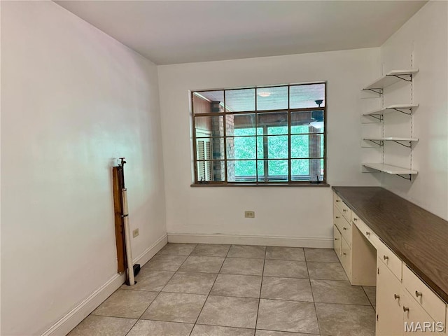 unfurnished dining area with baseboards and light tile patterned floors