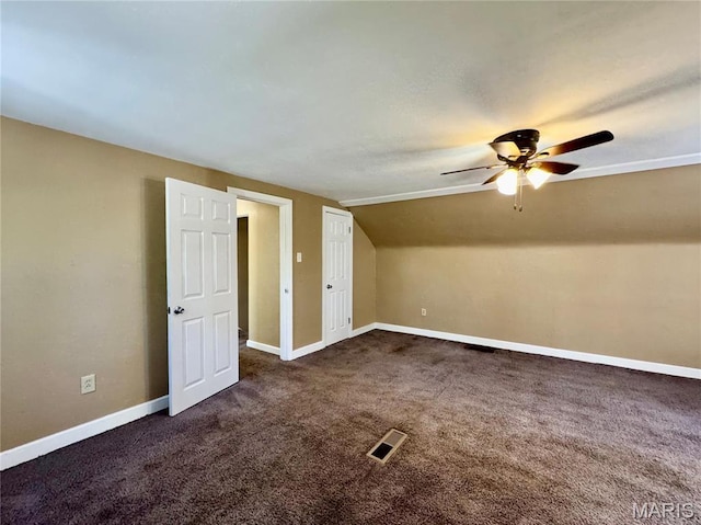 additional living space featuring a ceiling fan, dark colored carpet, baseboards, and vaulted ceiling