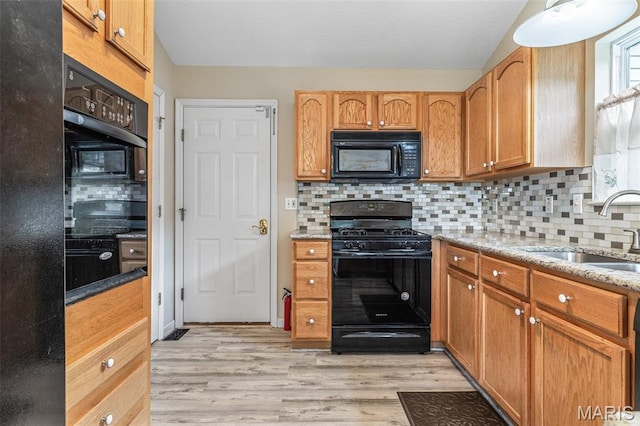 1421 N Woods Dr, Festus, MO 63028 - kitchen featuring black appliances, a sink, light wood finished floors, backsplash, and light stone countertops