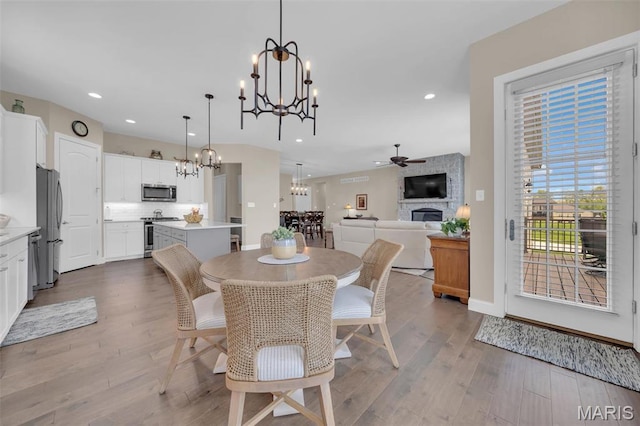 501 Upper Ridgepointe Ct, Lake St Louis, MO 63367 - dining room featuring a chandelier, a large fireplace, wood finished floors, recessed lighting, and a ceiling fan