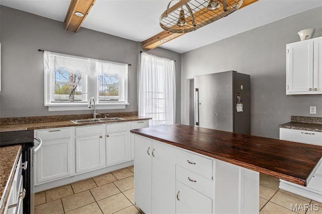 323 N Division St, Bonne Terre, MO 63628 - kitchen featuring a sink, butcher block counters, stainless steel appliances, beam ceiling, and light tile patterned floors