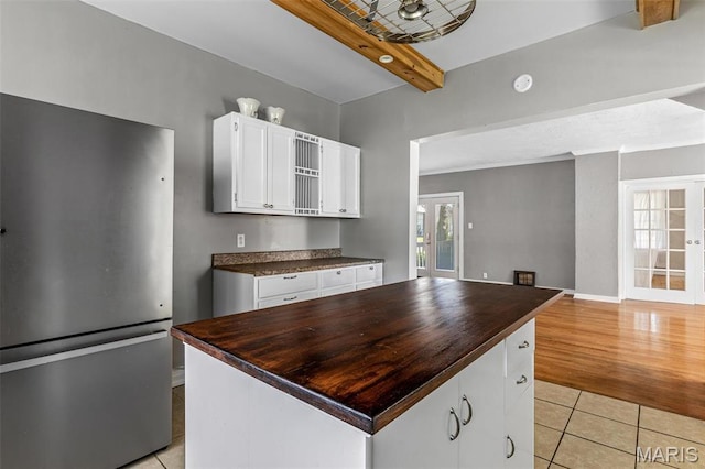 323 N Division St, Bonne Terre, MO 63628 - kitchen featuring freestanding refrigerator, white cabinets, light tile patterned floors, beam ceiling, and french doors