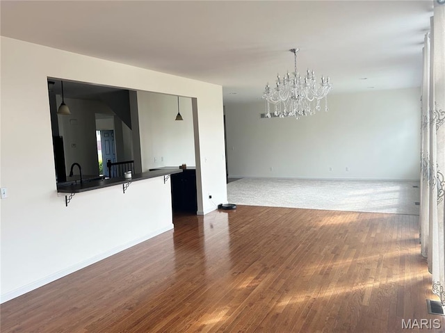 833 Harding St, Saint Peters, MO 63376 - unfurnished living room with a chandelier, dark wood-style flooring, baseboards, and a sink