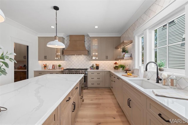 705 W Lockwood Ave, Glendale, MO 63122 - kitchen featuring premium range hood, a sink, decorative backsplash, hanging light fixtures, and glass insert cabinets