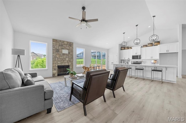 6345 Gibison Rd, Troy, MO 63379 - living room with a ceiling fan, light wood-style flooring, a stone fireplace, and high vaulted ceiling