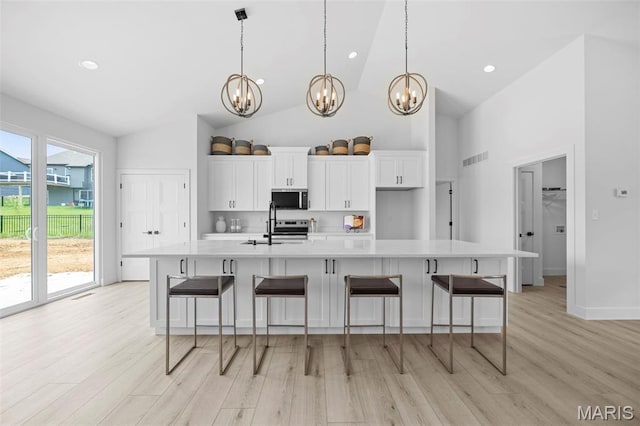 6345 Gibison Rd, Troy, MO 63379 - kitchen with stainless steel appliances, a chandelier, high vaulted ceiling, light countertops, and white cabinets