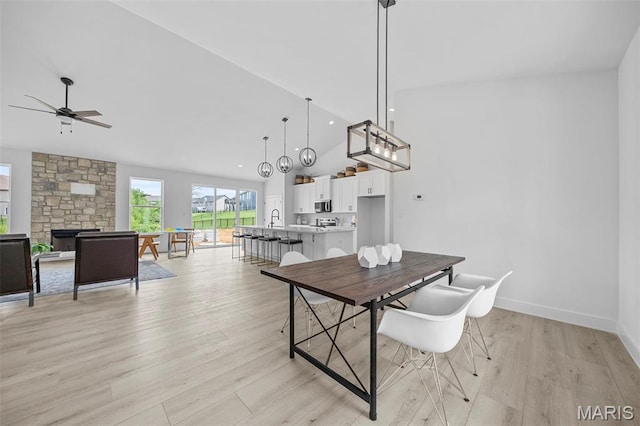 6345 Gibison Rd, Troy, MO 63379 - dining space with light wood-style flooring, ceiling fan, a stone fireplace, high vaulted ceiling, and baseboards