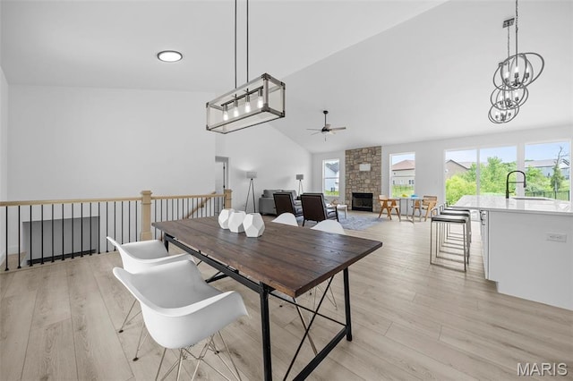 6345 Gibison Rd, Troy, MO 63379 - dining room with ceiling fan, a stone fireplace, light wood finished floors, high vaulted ceiling, and a chandelier