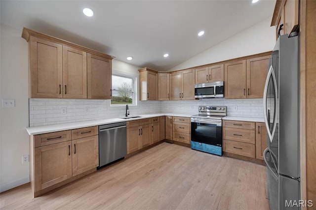 10204 Riehl Farm Dr, Potosi, MO 63664 - kitchen featuring appliances with stainless steel finishes, vaulted ceiling, decorative backsplash, light wood finished floors, and light countertops