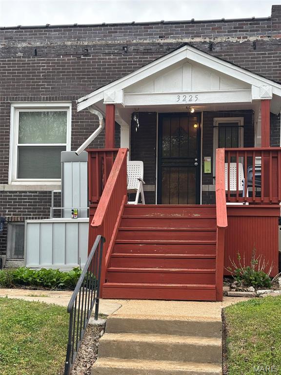 doorway to property featuring brick siding and a porch