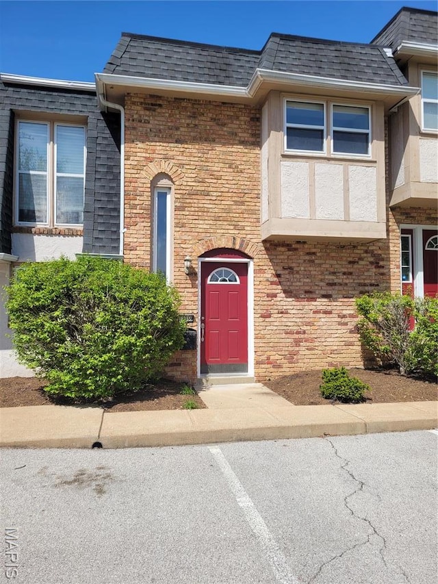 12859 Town And Four Dr Unit 12859, Creve Coeur, MO 63141 - view of exterior entry featuring brick siding, roof with shingles, mansard roof, and uncovered parking