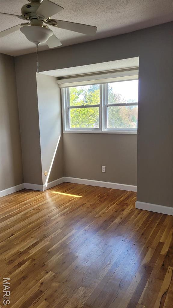 12859 Town And Four Dr Unit 12859, Creve Coeur, MO 63141 - empty room featuring a ceiling fan, baseboards, and wood-type flooring