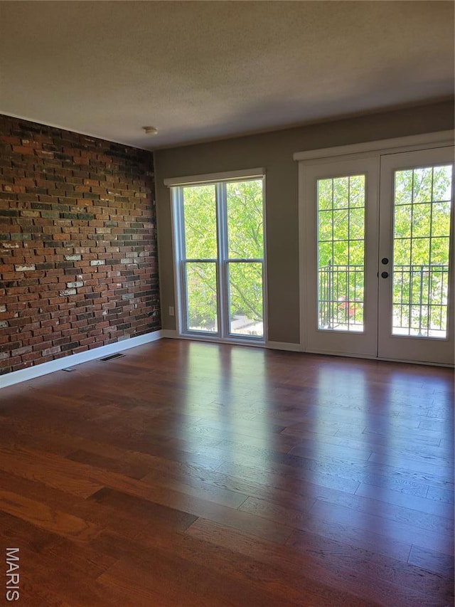 12859 Town And Four Dr Unit 12859, Creve Coeur, MO 63141 - unfurnished room featuring hardwood / wood-style floors, plenty of natural light, baseboards, french doors, and brick wall