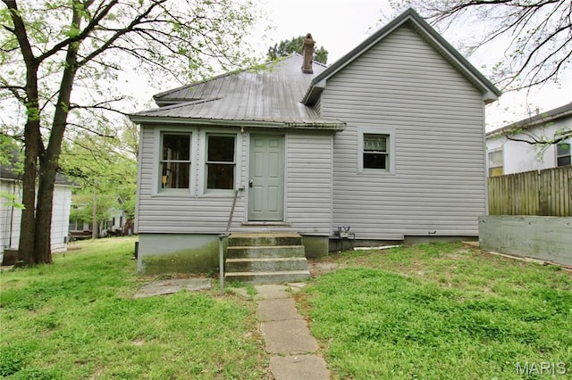 back of house featuring metal roof, a chimney, and entry steps