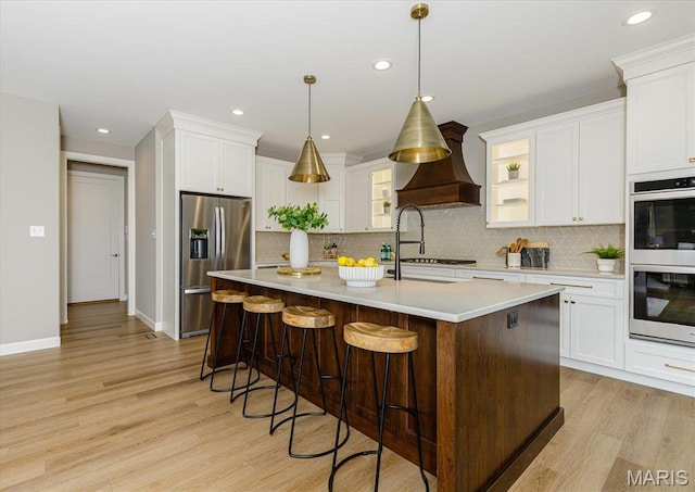 303 Clewer Park Ct, Lake St Louis, MO 63367 - kitchen featuring stainless steel appliances, a sink, premium range hood, light wood-style floors, and recessed lighting
