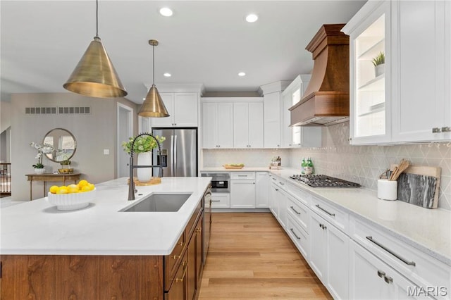 303 Clewer Park Ct, Lake St Louis, MO 63367 - kitchen with appliances with stainless steel finishes, a sink, custom exhaust hood, a center island with sink, and white cabinets