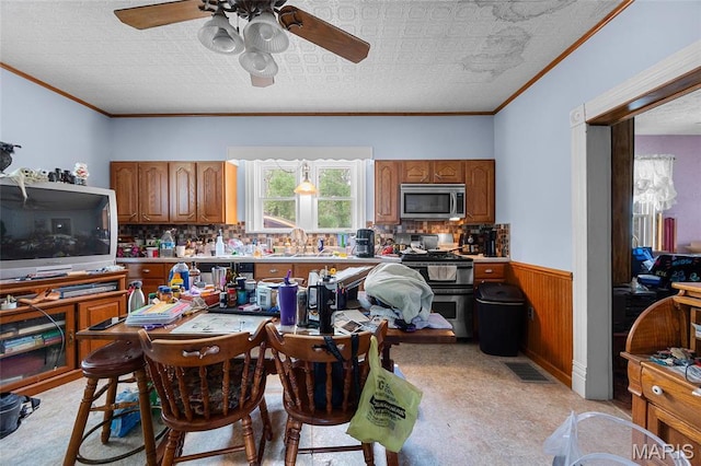 883 Biltmore St, Saint Genevieve, MO 63670 - dining room with ceiling fan, a wainscoted wall, ornamental molding, wooden walls, and light carpet