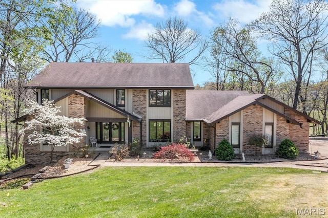mid-century modern home featuring brick siding, a shingled roof, and a front yard