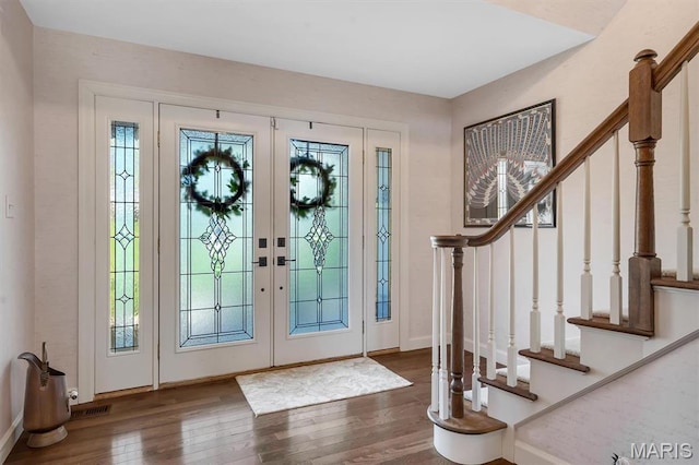 foyer with wood finished floors, stairway, baseboards, and french doors