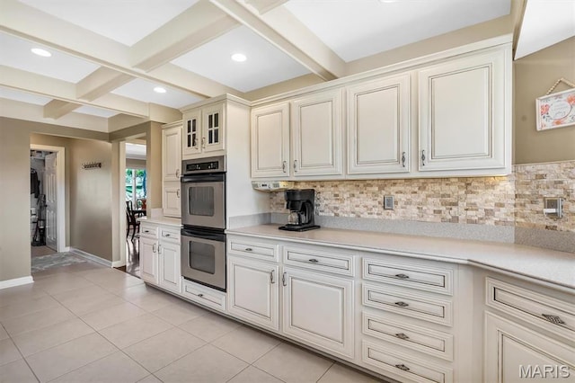kitchen featuring double oven, coffered ceiling, backsplash, light countertops, and beamed ceiling