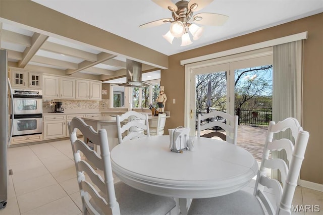 dining space with a ceiling fan, healthy amount of natural light, beam ceiling, coffered ceiling, and light tile patterned floors
