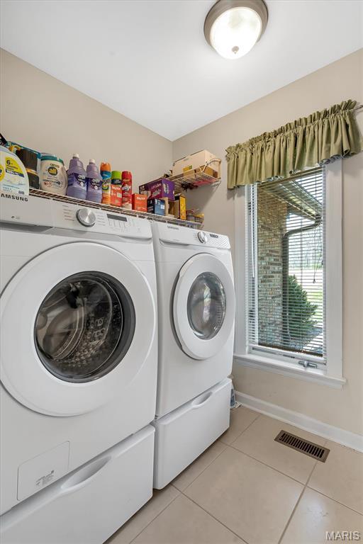 laundry area with light tile patterned floors, separate washer and dryer, and baseboards
