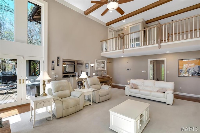 living area featuring a high ceiling, a ceiling fan, baseboards, beam ceiling, and french doors
